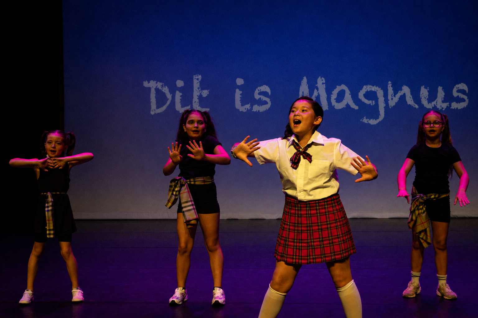 Vier kinderen zingen en dansen op het podium tijdens de musical Matilda
