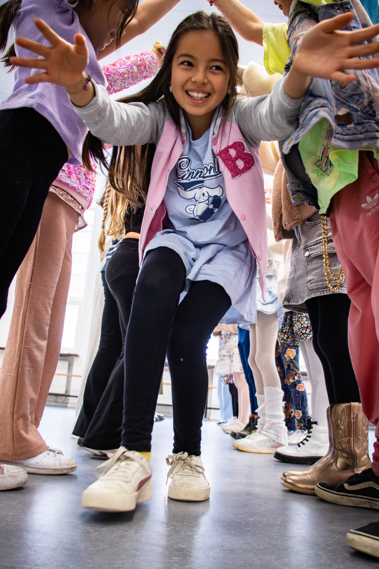 Lachend meisje danst door een poort van armen tijdens de dansles