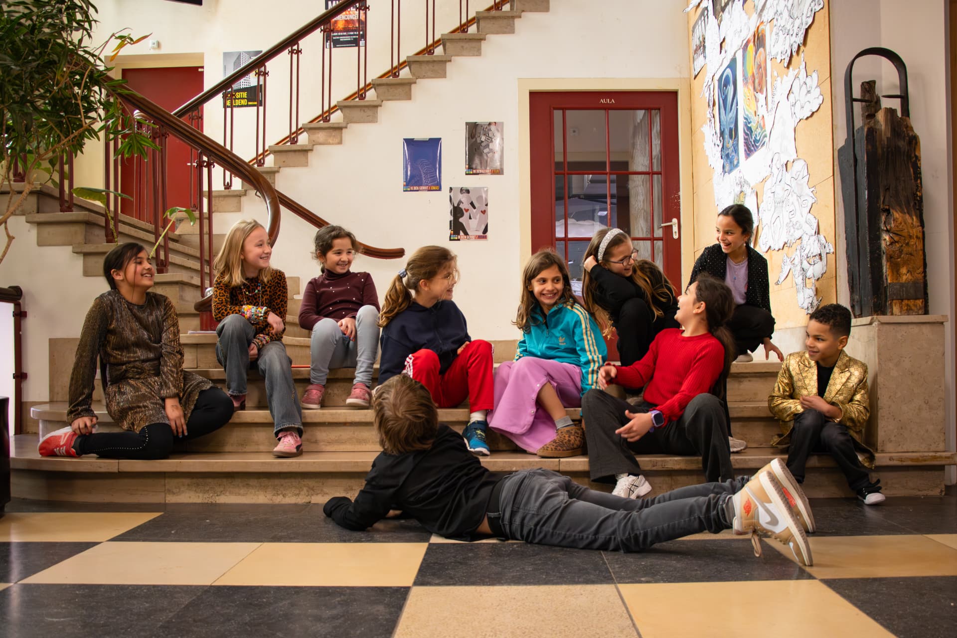 Kinderen zitten lachend op de trap in de gang tijdens de pauze