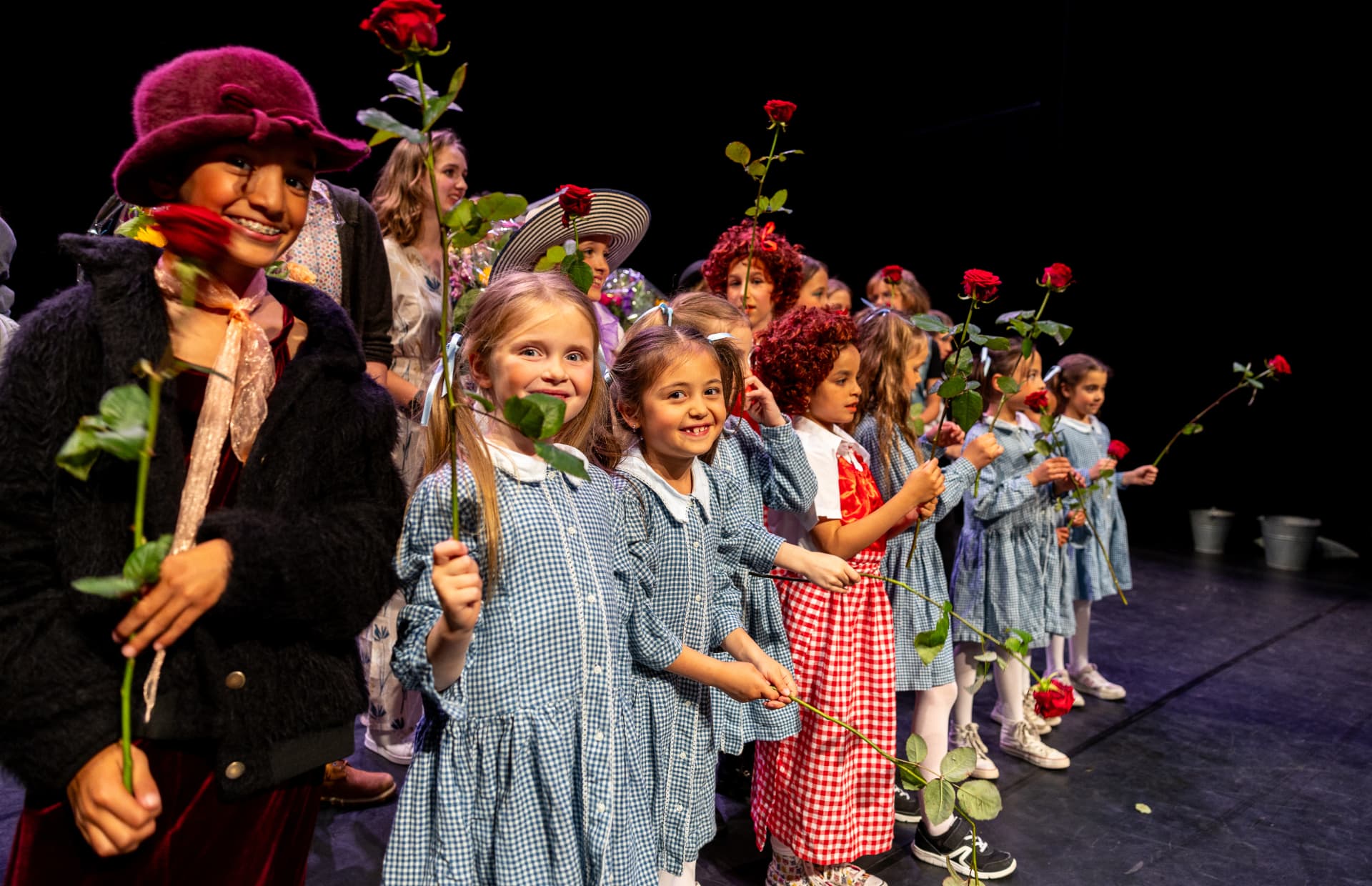 Kinderen staan in een rij met rode rozen tijdens de finale