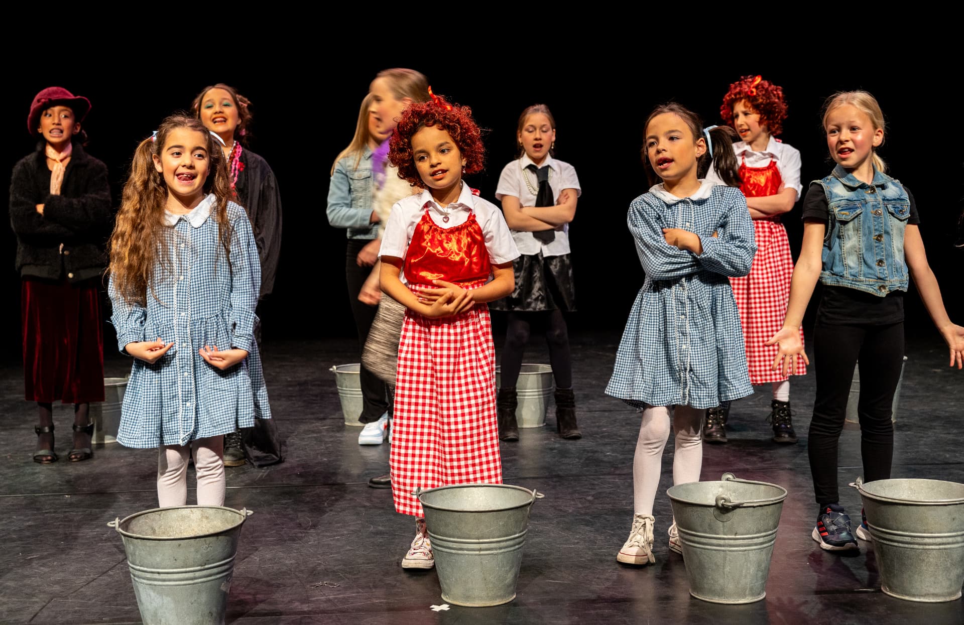 Kinderen in kostuum spelen samen een scène met emmers